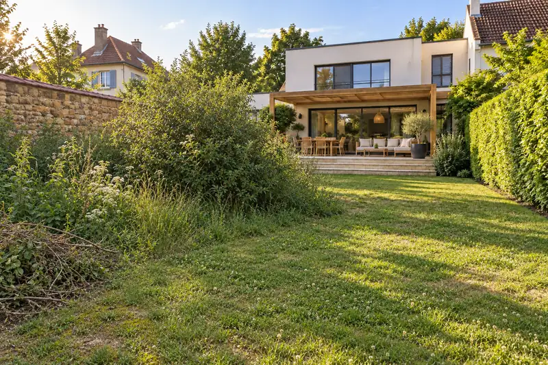 Avant : pelouse clairsemée, arbuste envahissant et herbes folles devant la même maison